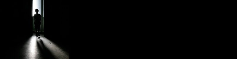 silhouette of a boy walking through a doorway on a black background