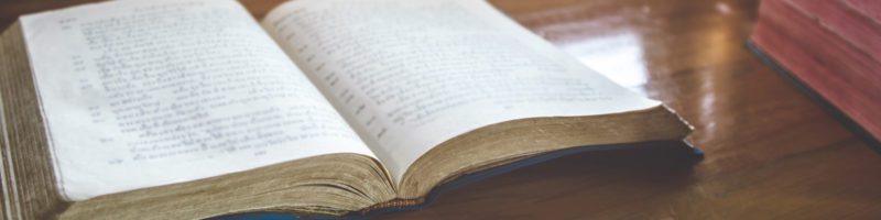 picture of an open Bible lit by a lamp and an open window