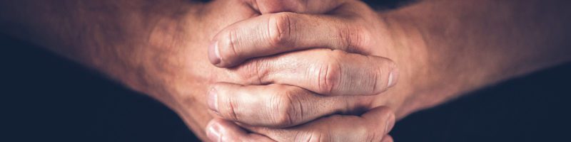 hands folded in prayer for a sermon titled battling our demons with pastor matthew piersanti
