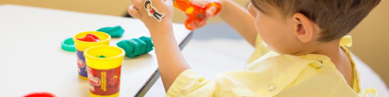 child in hospital playing with toys and playdoh